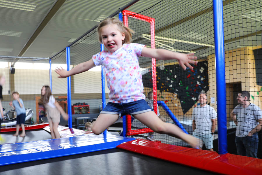 Kleines Mädchen springt fröhlich auf einem großen Trampolin.